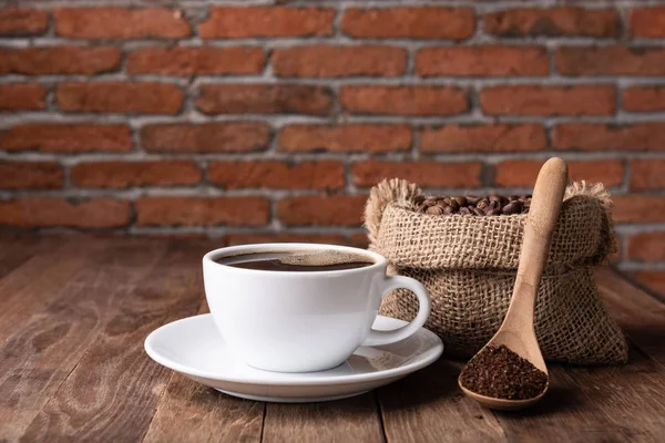 Taza de café, café molido y granos de café en arpillera sobre tabla de madera — Foto de Stock