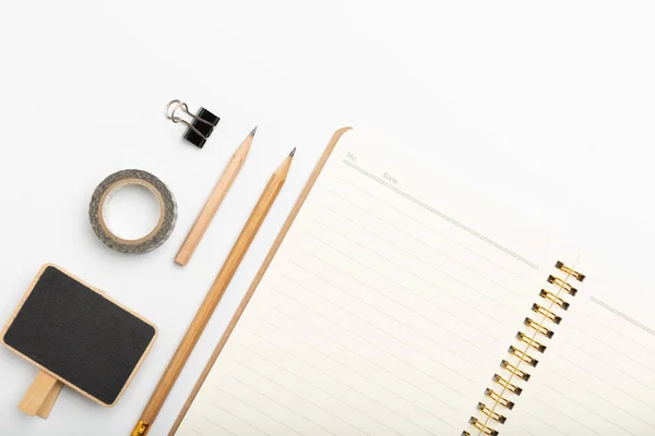 Espacio de trabajo con cuaderno, lápiz y bpard negro sobre fondo blanco — Foto de Stock