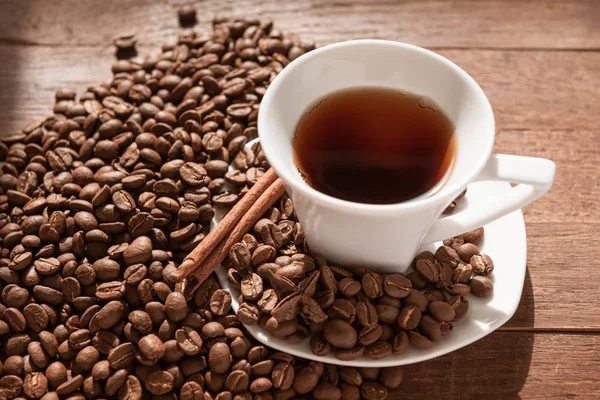 Tazza di caffè bianca e chicchi di caffè su tavola di legno — Foto Stock