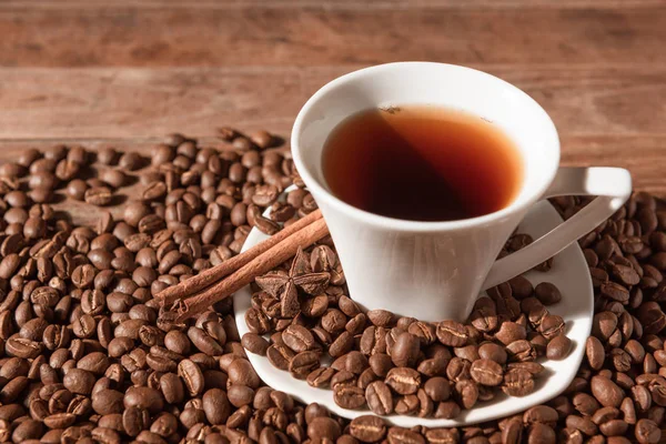 Bílý šálek kávy a kávová zrna na dřevěném stole — Stock fotografie