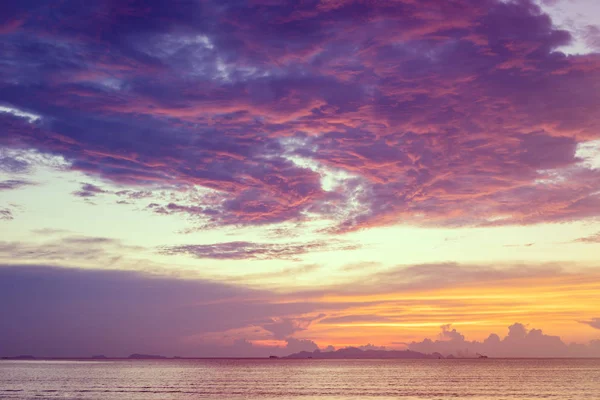 Pôr-do-sol na praia com mar azul e nuvens roxas amarelas — Fotografia de Stock