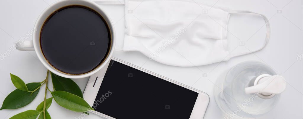 Work from home New Normal concept due to Covid-19 or Coronavirus with antibacterial hand gel, cloth mask,coffee cup, and  mobile phone on white background,flat lay