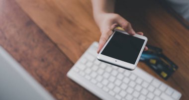 İnternet bankacılığı ve çevrimiçi alışveriş konsepti için bilgisayarlı kredi kartı ve cep telefonu kullanan kadın..