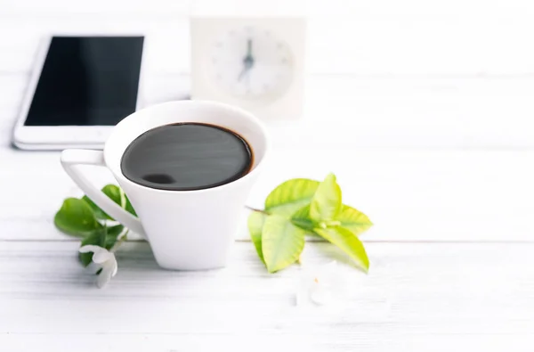 Arbetsplatssammansättning Med Kaffekopp Mobiltelefon Väckarklocka Och Blommor Vitt Träbord — Stockfoto