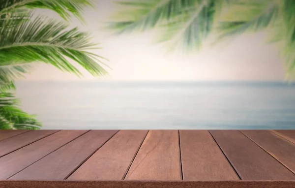 背景にぼやけたビーチの空と前景にヤシの葉を持つ茶色の木製の板 夏のコンセプト — ストック写真