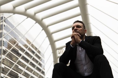 İş düşünerek ve street yürüyüş üzerinde oturan işadamı.