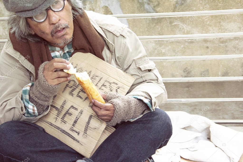 homeless man eating old bread on walkway street in the capital city.