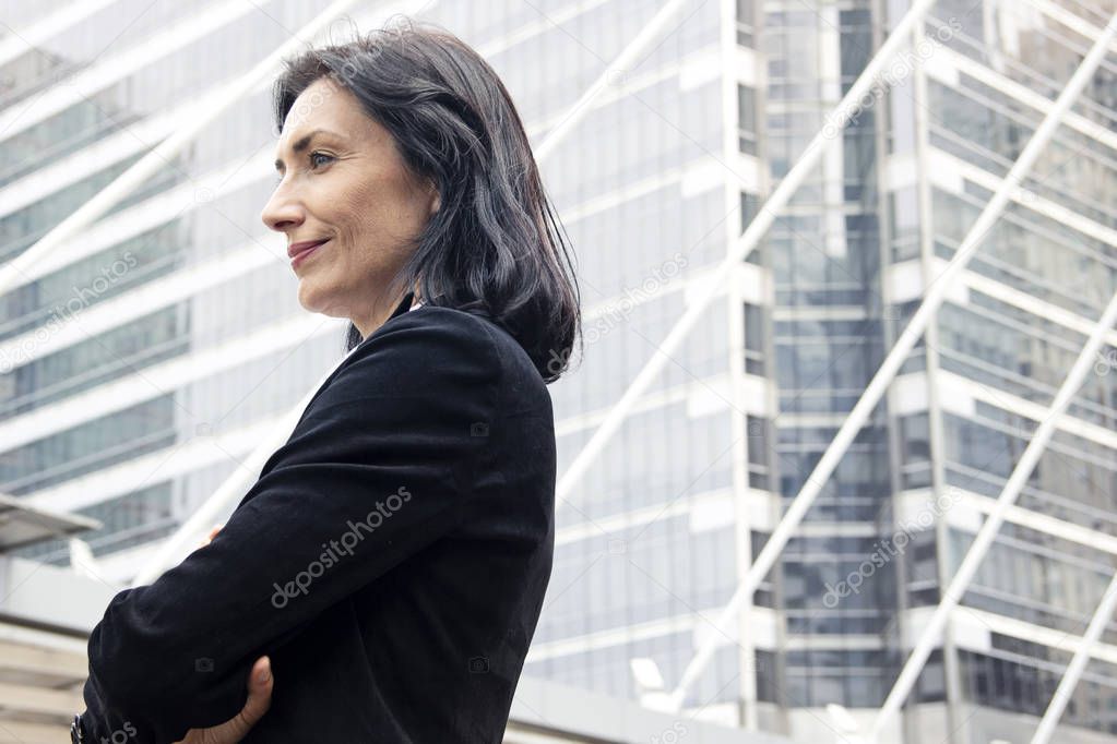 Beautiful business woman smiling and looking offices building background, blue color shape.
