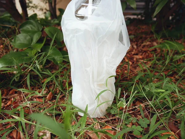 Water Bottle and Plastic Bag on cement texture in the green park.