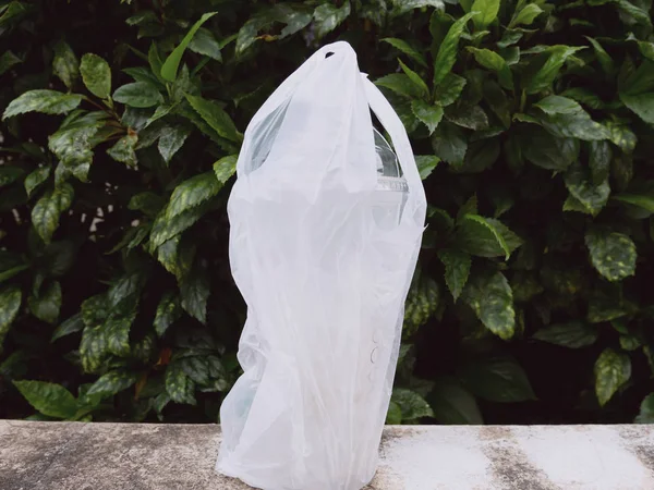 Water Bottle and Plastic Bag on cement texture in the green park.