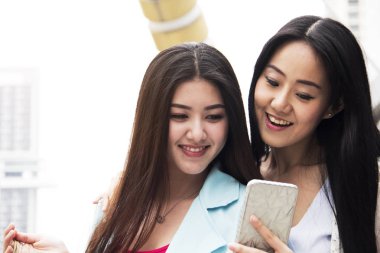 Hareket eden telefon aygıt ve ofis binası arka plan oynamaya yakın çekim güzel iki kadın.