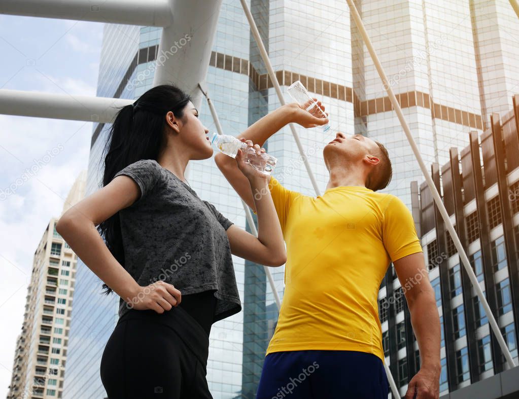 Athletes are drinking water on walking street and building background.