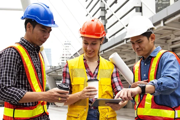 Engineering team holding smart phone and planning construction for work. Retouch and blur logo smart phone device.