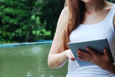 Parkta akıllı telefon oynayan genç kadın.