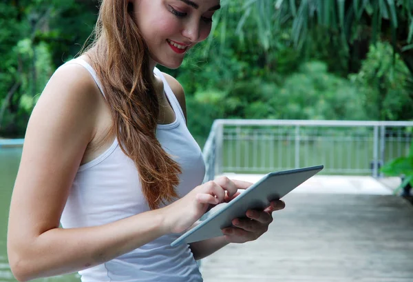 Seyahat ve akıllı tablet cihaz genel parkta tutan güzel kız.