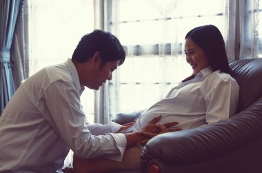 Kocası olan yakın plan hamile bir kadın ve beyaz arka planda sarılıyor.