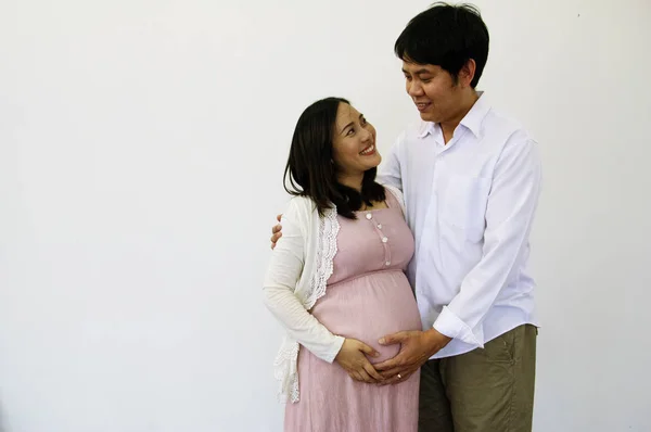Close-up pregnant woman with husband and hug on white background.