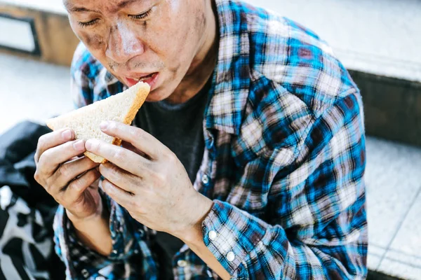 Yakın çekim evsiz adam portre yürüyüş sokakta ekmek yeme.