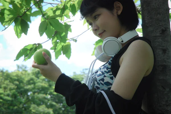 美丽的亚洲运动妇女拿着绿色的苹果 走在公园 — 图库照片