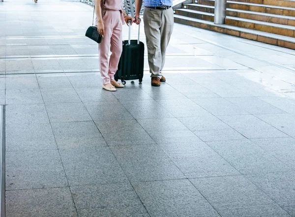 senior couple drag luggage traveling on walking street
