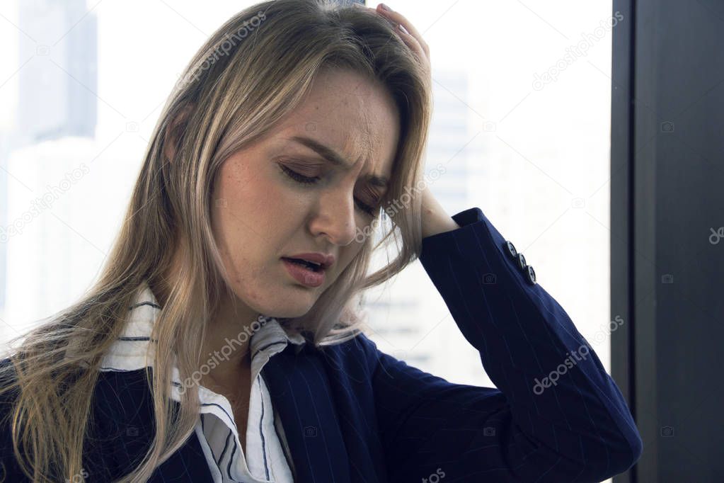 Close-up beautiful business woman sadness and hand on head in office and building background.