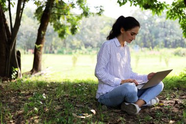 Genç ve güzel bir kadın yaz tatilinde parkta çalışıyor..