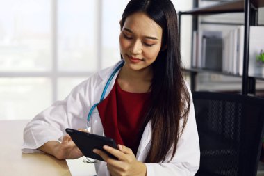 Mutlu Asyalı genç doktor kadın hastanede gülümsüyor..