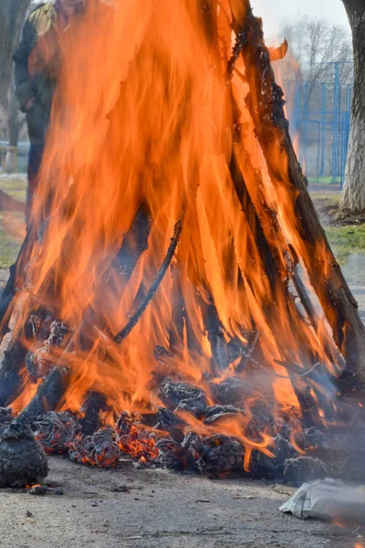 Slavische vakantie eind van de winter. Een grote terry pop van stro brandt. Zwarte rook is zichtbaar Stockfoto