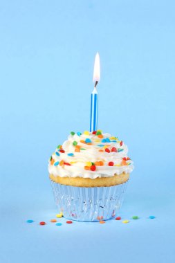 Yanan mum ve serpinti ile buzlu doğum günü cupcake