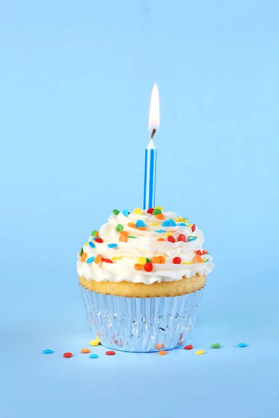 Iced birthday cupcake with with lit candle and sprinkles Royalty Free Stock Images