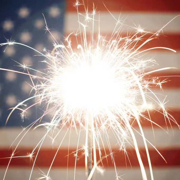 アメリカの国旗の前で燃えている線香花火を照らす — ストック写真