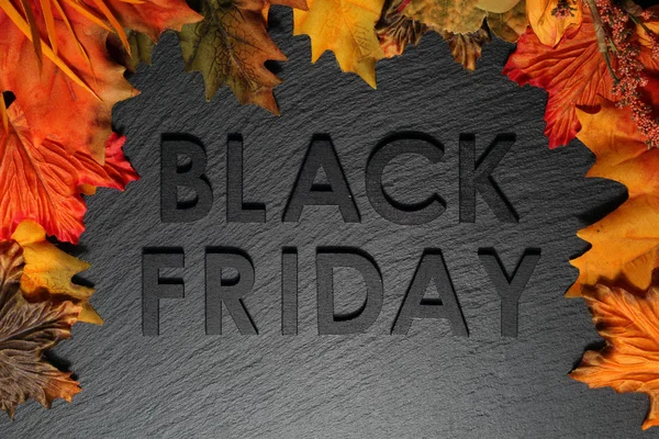 黒いスレートの背景に秋の葉を持つブラックフライデーのテキスト — ストック写真