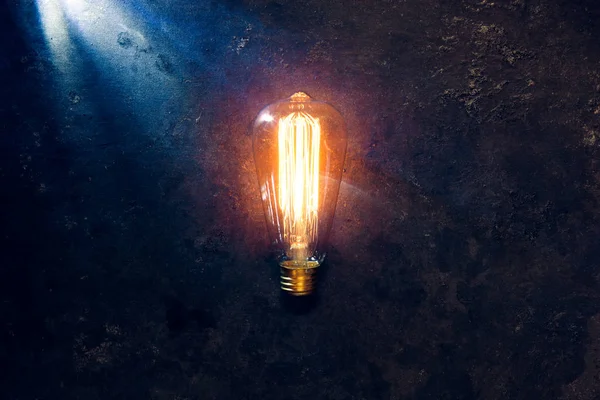 Vintage lâmpada velha brilhante amarelo no fundo escuro áspero . — Fotografia de Stock
