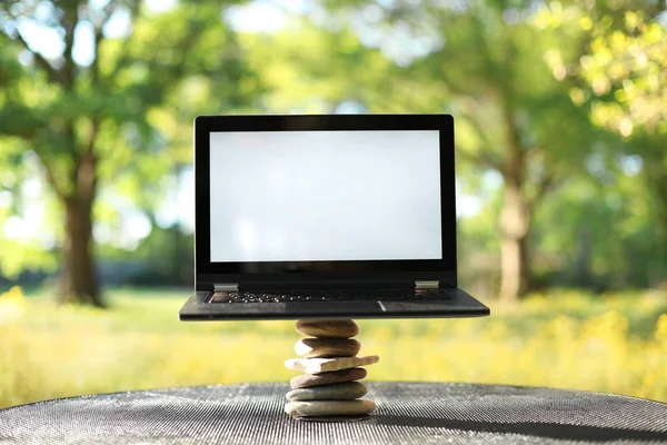 Laptop s prázdnou obrazovkou venku vyvažování na kamenech obklopen — Stock fotografie