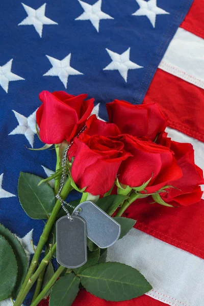 Amerikai zászló rózsákkal és üres katonai dögcédulákkal — Stock Fotó