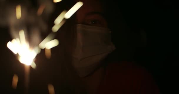 의료용 마스크를 불꽃이 날리는 반짝이는 스파클러를들고 코로나 바이러스가 유행하던 기념하는 — 비디오