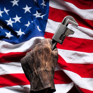 Amerikan Bayrağı 'nın üzerinde yıpranmış ve kirli altın boru anahtarı tutan