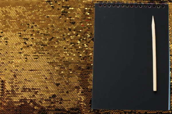 Notebook Prázdnými Černými Prostěradly Dřevěnou Škrabkou Zářivě Lesklém Pozadí Zlatých — Stock fotografie