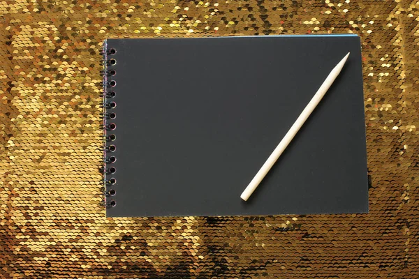 Notebook Prázdnými Černými Prostěradly Dřevěnou Škrabkou Zářivě Lesklém Pozadí Zlatých — Stock fotografie