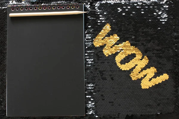 黒いスパンコールの背景に金のスパンコールのうわー文字と黒いシートとエントリのための木製のスクレーパースペースとメモ帳 — ストック写真