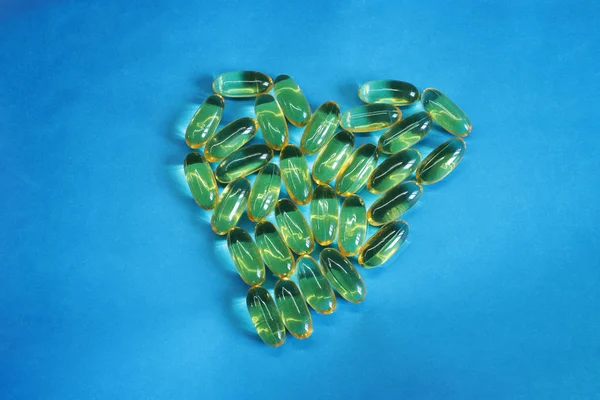 Vitamins yellow fish oil oval, healthy fish oil lie on a bright background in the form of a heart and free space for records