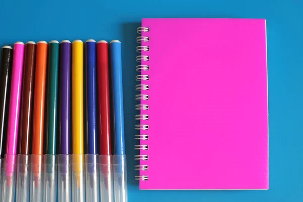 Notepad and a lot of multi-colored markers on a bright background