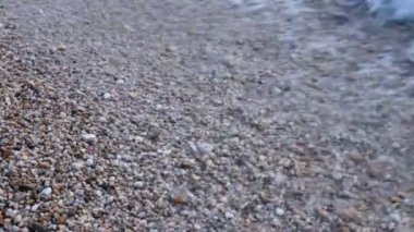 Küçük çakıl taşları ve berrak su dalgaları ile sahil
