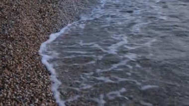 Küçük çakıl taşları ve berrak su dalgaları ile sahil