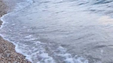 Küçük çakıl taşları ve berrak su dalgaları ile sahil