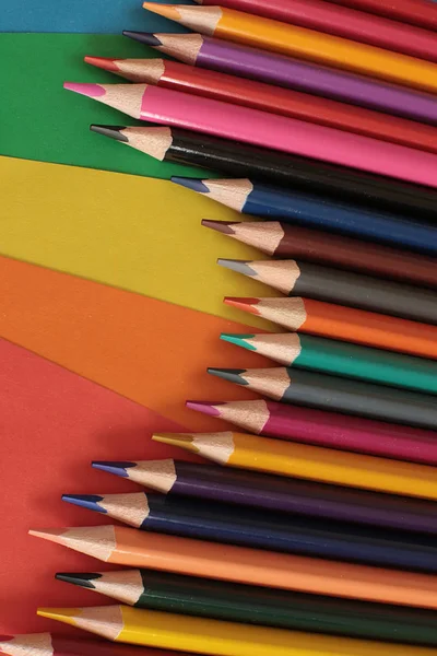 Colored pencils for drawing and creativity on a bright rainbow background school equipment of a real artist