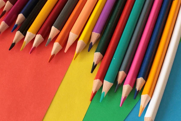 Colored pencils for drawing and creativity on a bright rainbow background school equipment of a real artist
