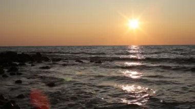 Deniz koyu büyük taşlar ve dalgalar gün batımı ve küçük esinti
