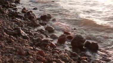 Deniz koyu büyük taşlar ve dalgalar gün batımı ve küçük esinti