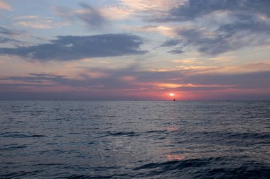 Denizde parlak gün batımı hava ve su dar bir kıyı şeridi çok, su yakın şafak gökyüzünde güneş renkleri bir degrade